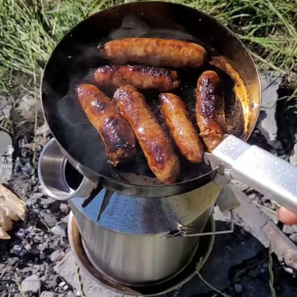 Kiełbaski smażone na pokrywce-patelni nad paleniskiem czajnika Kelly Kettle